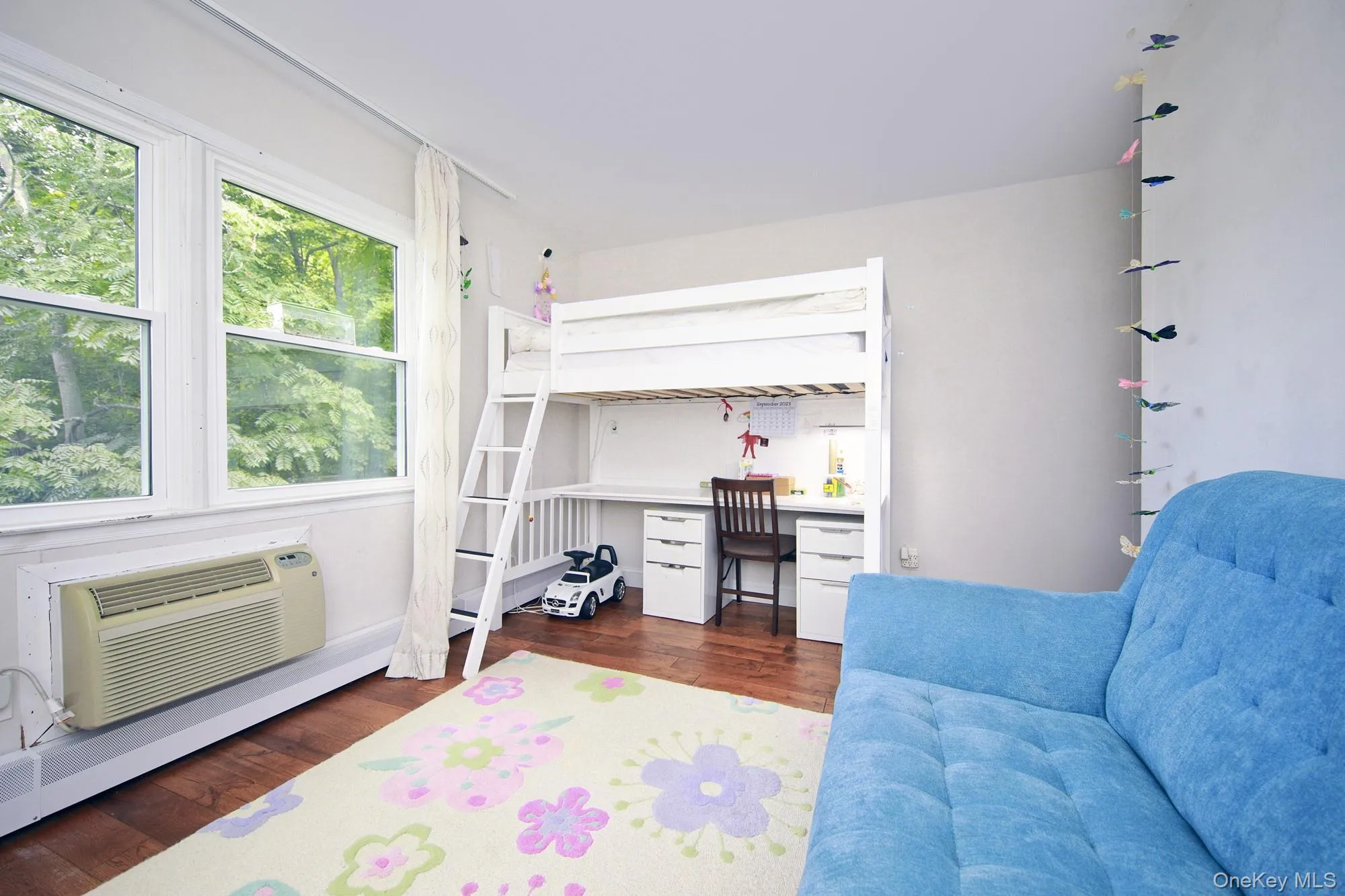 Bedroom with dark wood-type flooring, a desk, a baseboard heating unit, and a wall unit AC Bedroom with dark wood-type flooring, a desk, a baseboard heating unit, and a wall unit AC