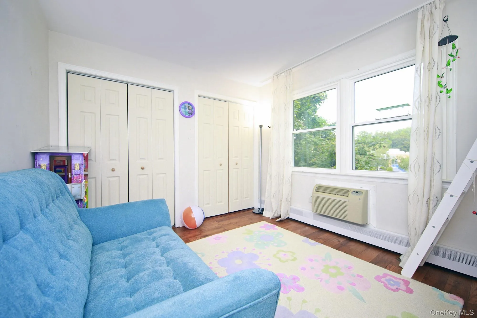 Sitting room featuring dark wood finished floors, a wall mounted air conditioner, and a baseboard radiator Sitting room featuring dark wood finished floors, a wall mounted air conditioner, and a baseboard radiator