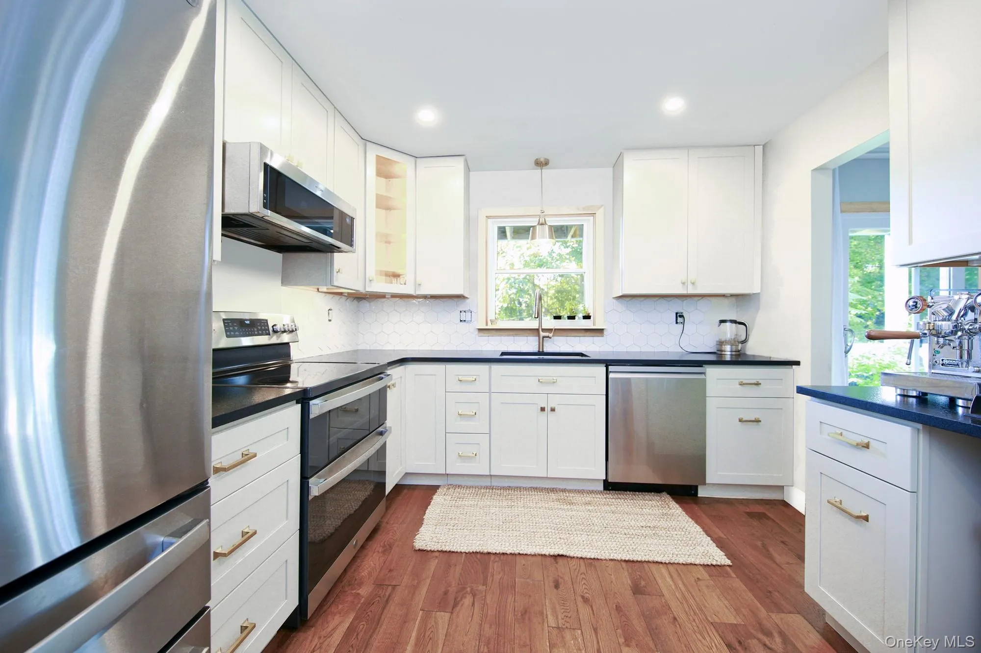 Kitchen featuring stainless steel appliances, hanging light fixtures, white cabinetry, dark wood-style floors, and recessed lighting Kitchen featuring stainless steel appliances, hanging light fixtures, white cabinetry, dark wood-style floors, and recessed lighting