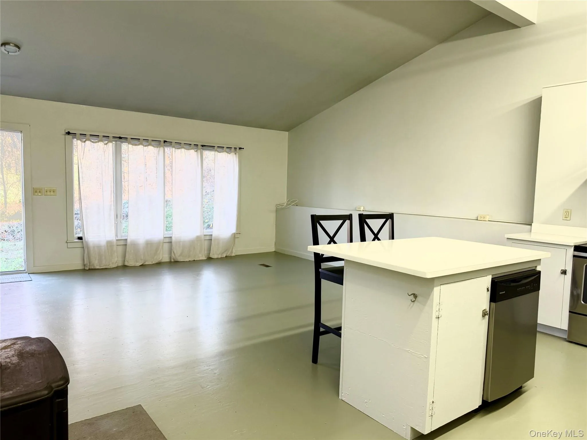 Kitchen featuring a kitchen bar, light countertops, white cabinets, stainless steel appliances, and open floor plan Kitchen featuring a kitchen bar, light countertops, white cabinets, stainless steel appliances, and open floor plan