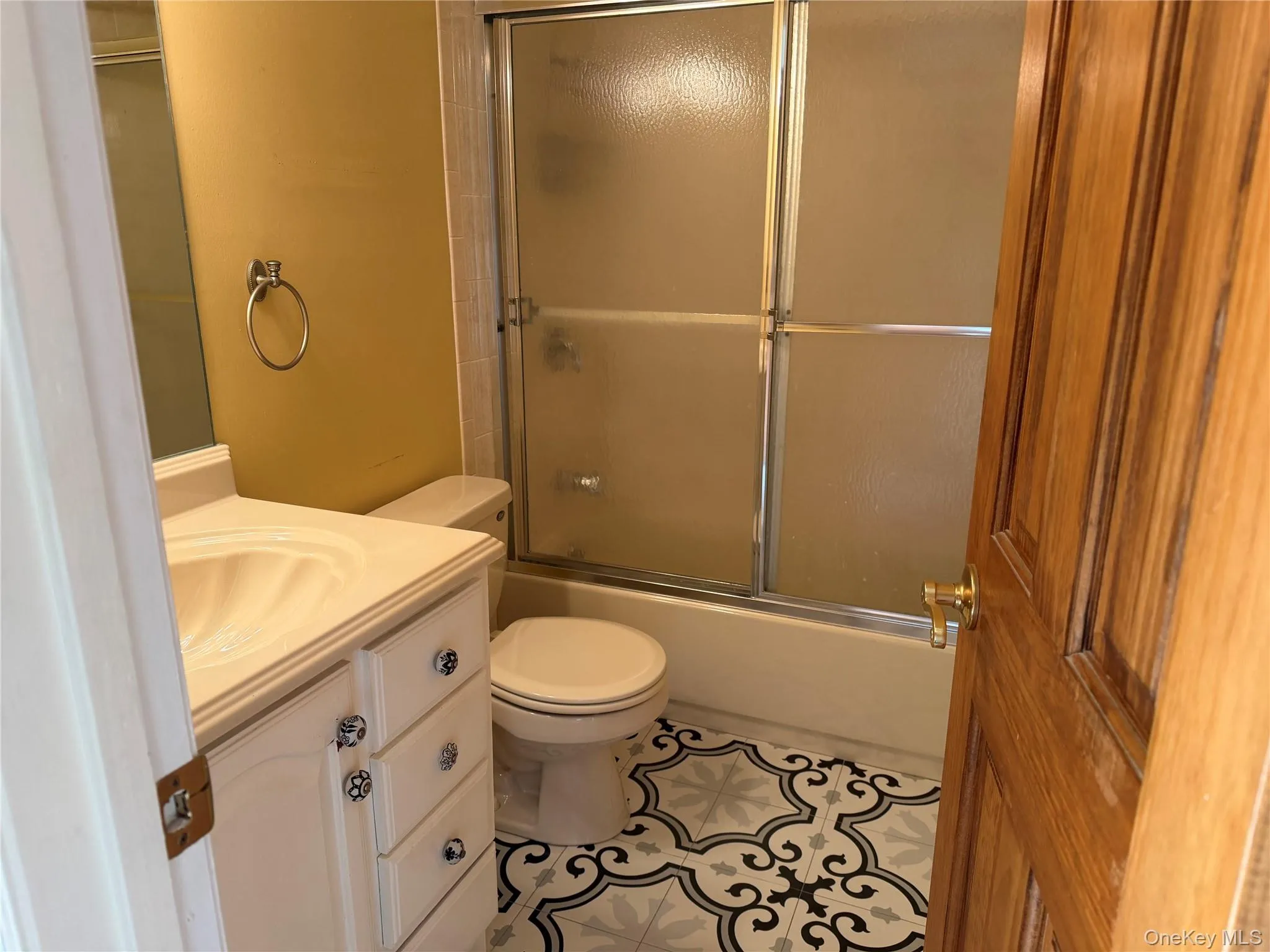 Bathroom with vanity, enclosed tub / shower combo, and tile patterned flooring Bathroom with vanity, enclosed tub / shower combo, and tile patterned flooring