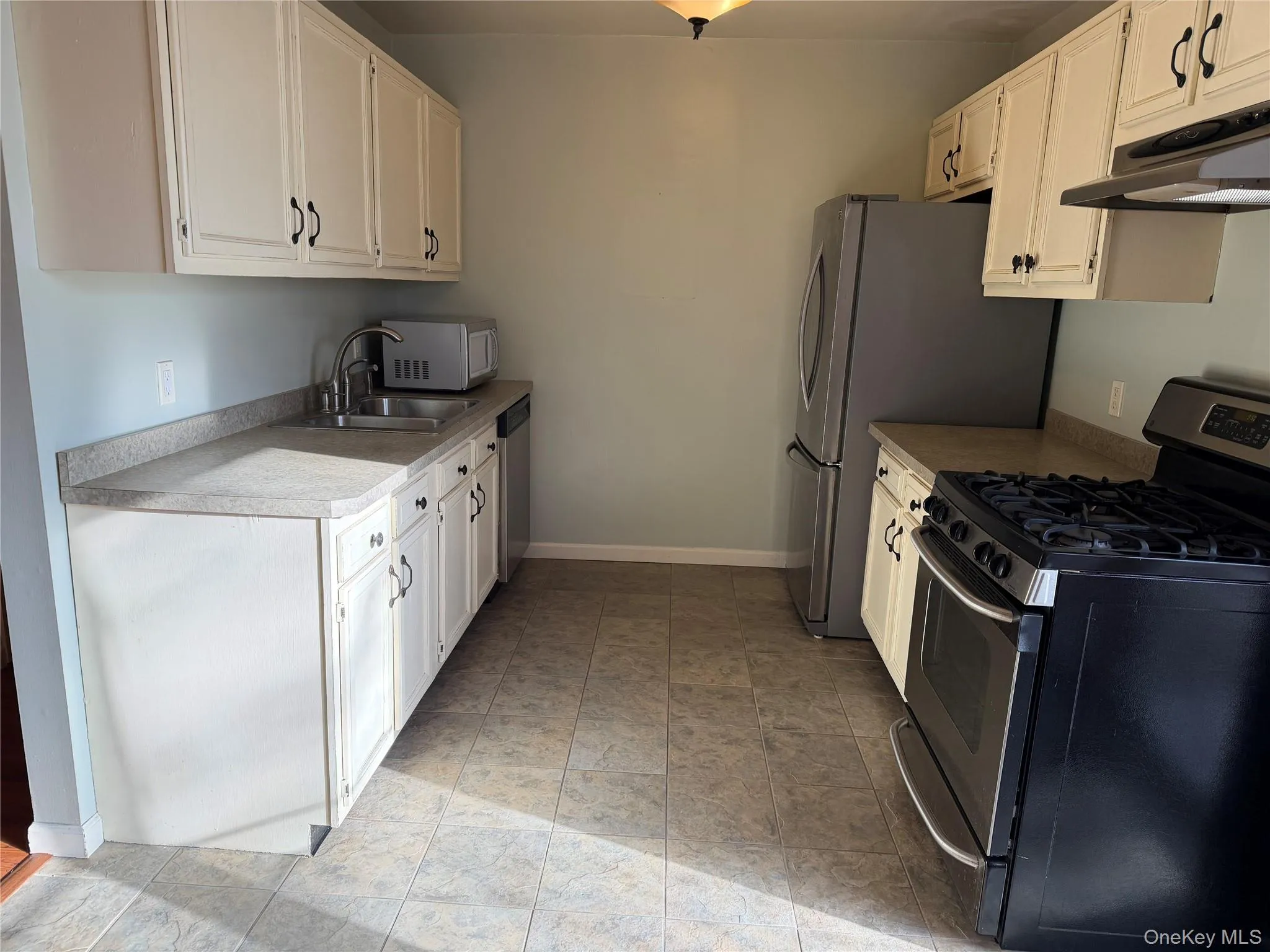 Kitchen with stainless steel appliances, white cabinets, light countertops, and under cabinet range hood Kitchen with stainless steel appliances, white cabinets, light countertops, and under cabinet range hood