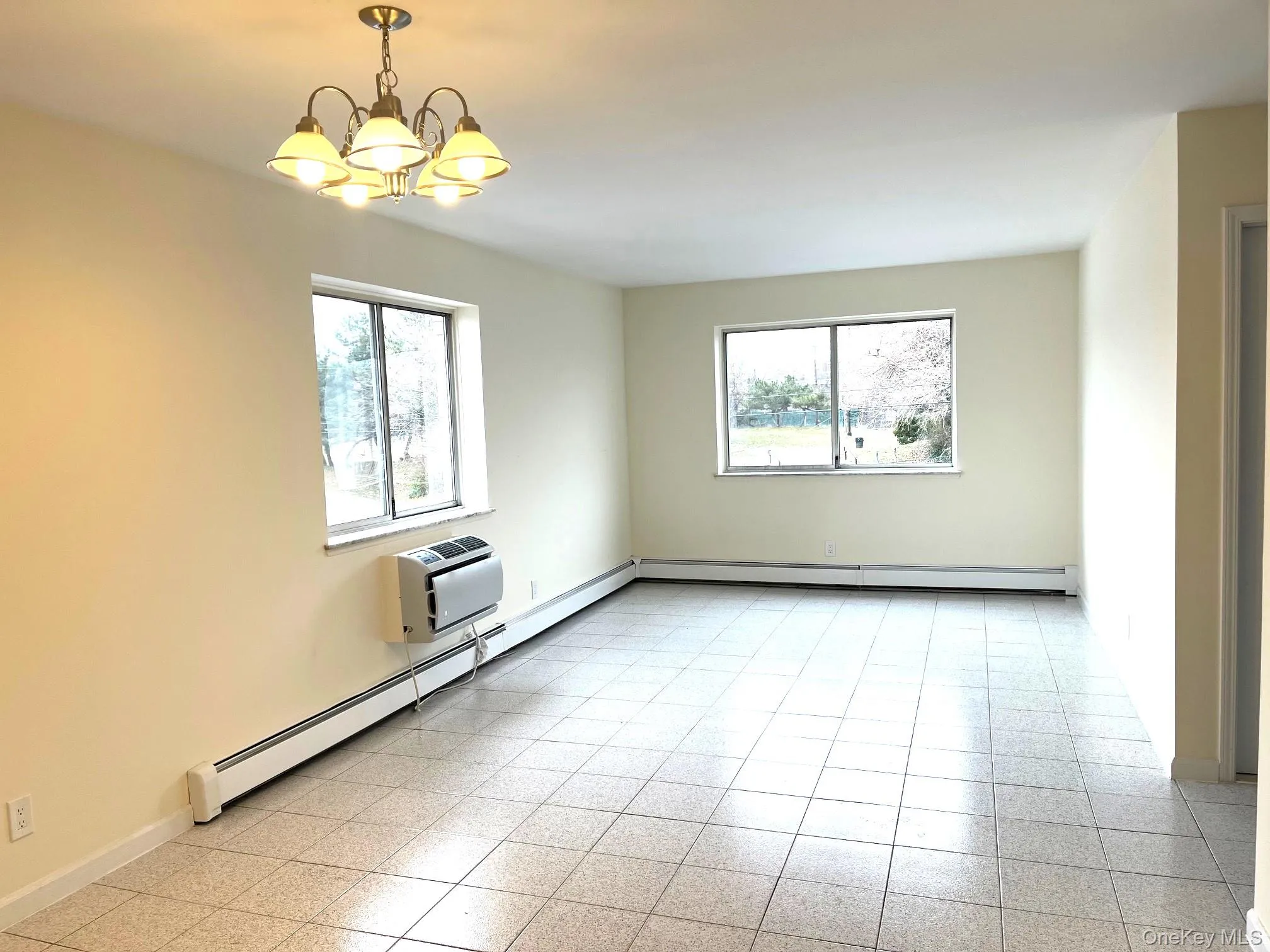 Unfurnished room with a baseboard radiator, plenty of natural light, a baseboard heating unit, and a chandelier Unfurnished room with a baseboard radiator, plenty of natural light, a baseboard heating unit, and a chandelier