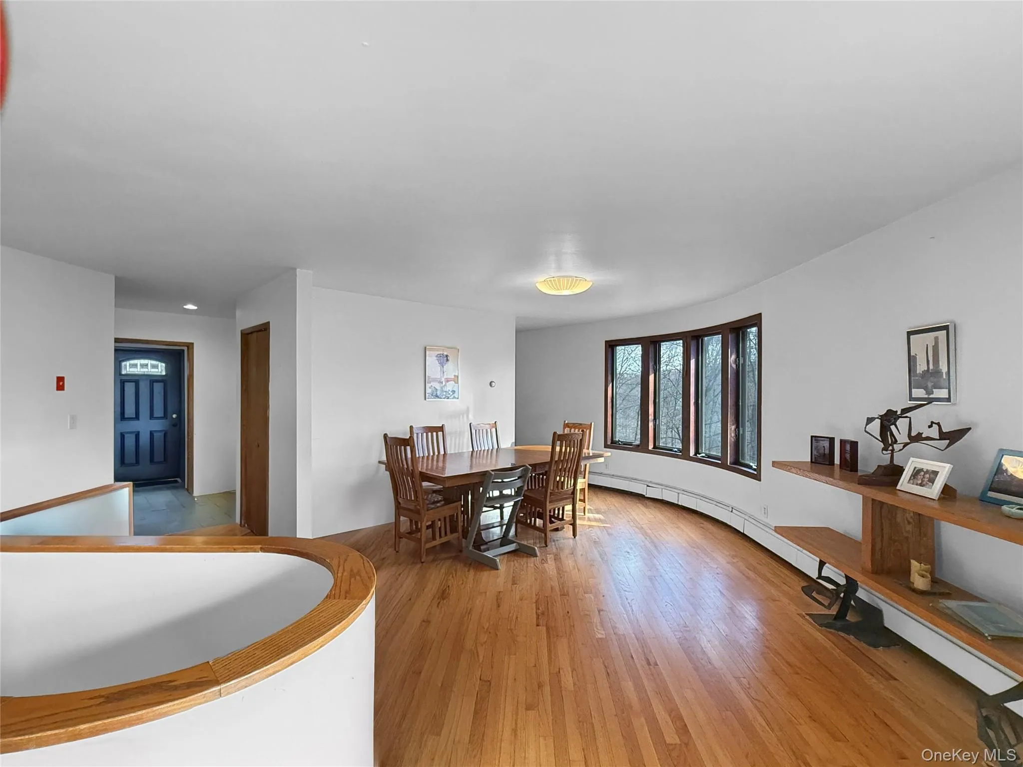 Dining area with open floor plan, curved windows & circular stairwell to lower level Dining area with open floor plan, curved windows & circular stairwell to lower level