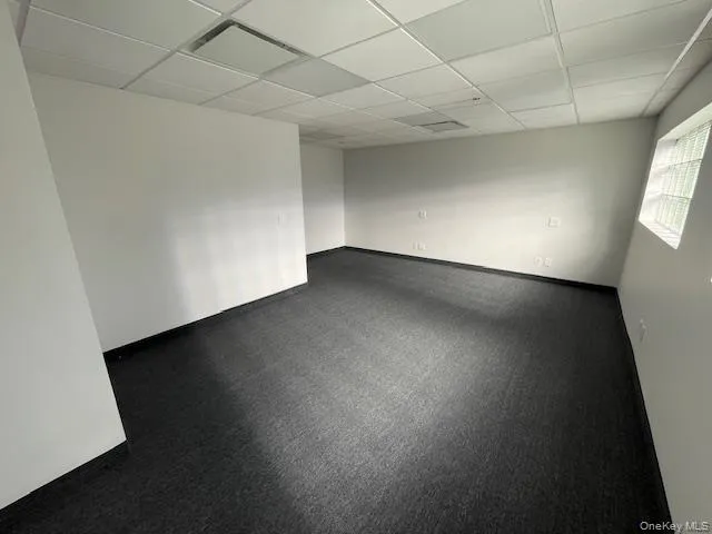 Spare room with a drop ceiling and carpet flooring Spare room with a drop ceiling and carpet flooring