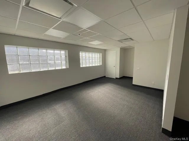 Spare room featuring a drop ceiling and dark carpet Spare room featuring a drop ceiling and dark carpet