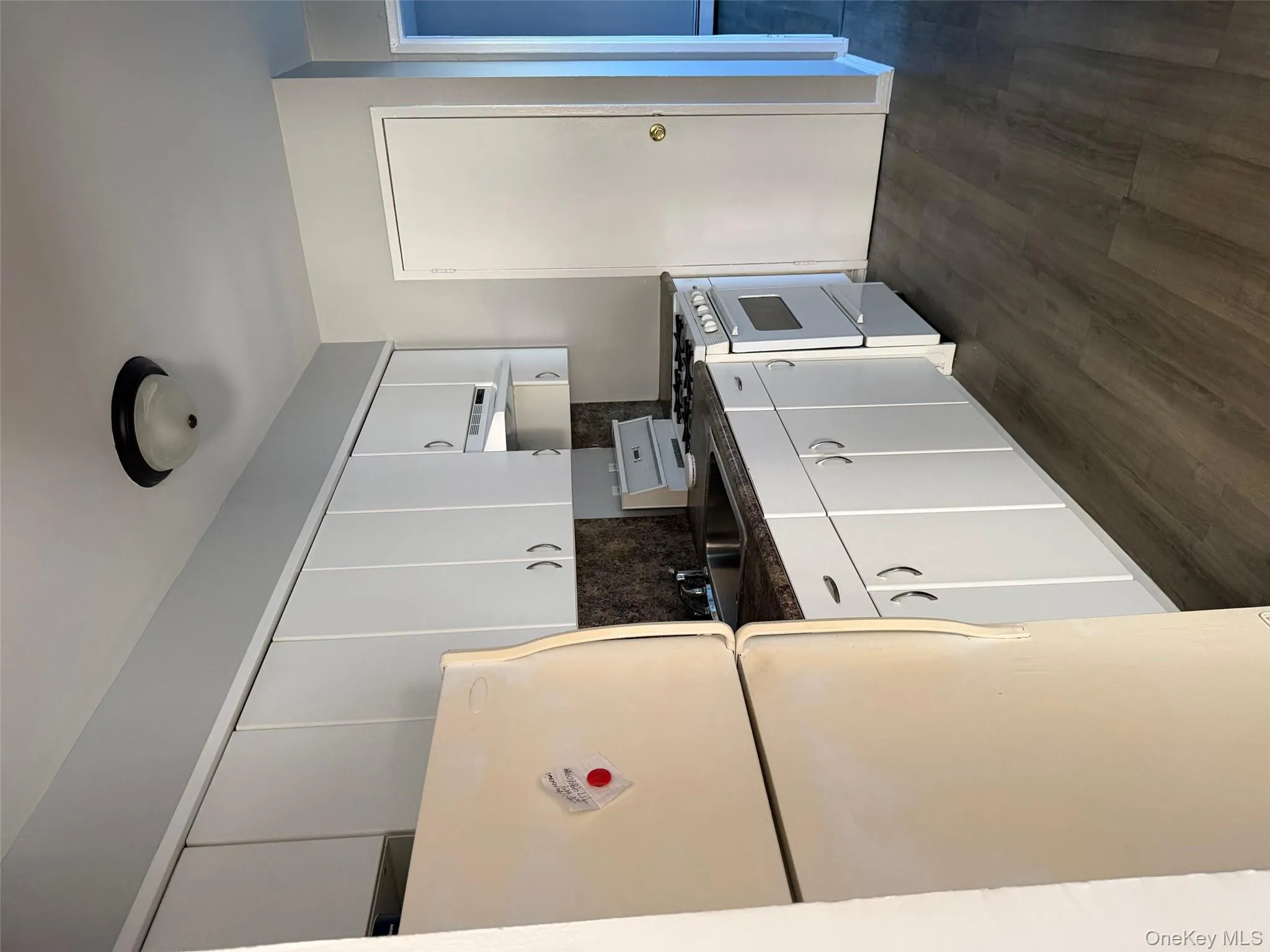 Kitchen with dark countertops, refrigerator, range, white cabinetry, and dark wood finished floors Kitchen with dark countertops, refrigerator, range, white cabinetry, and dark wood finished floors