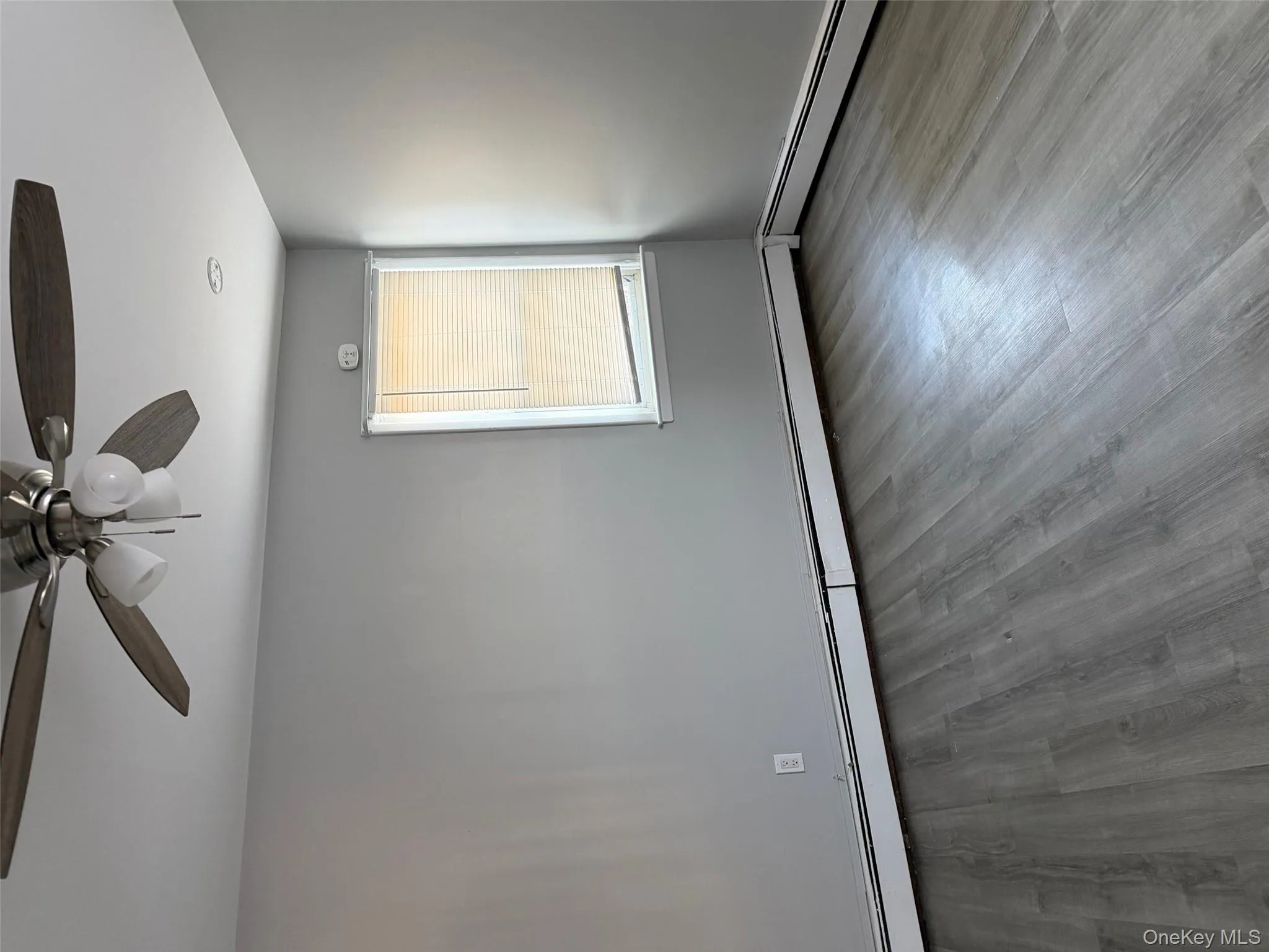 Empty room with a baseboard radiator, light wood finished floors, and a ceiling fan Empty room with a baseboard radiator, light wood finished floors, and a ceiling fan