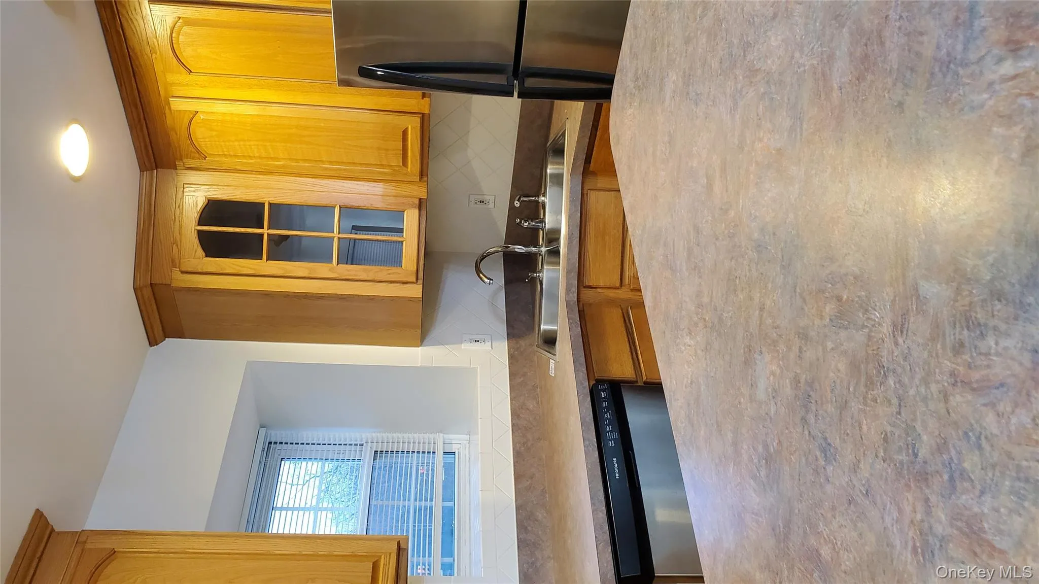 Kitchen with fridge, dishwasher, glass insert cabinets, brown cabinetry, and light countertops Kitchen with fridge, dishwasher, glass insert cabinets, brown cabinetry, and light countertops