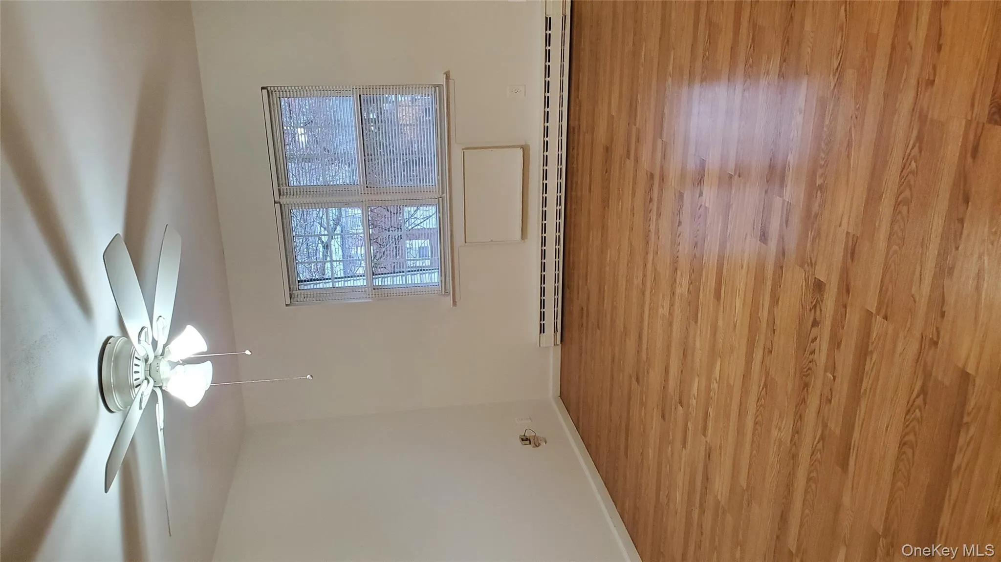 Empty room with light wood finished floors, baseboard heating, and ceiling fan Empty room with light wood finished floors, baseboard heating, and ceiling fan