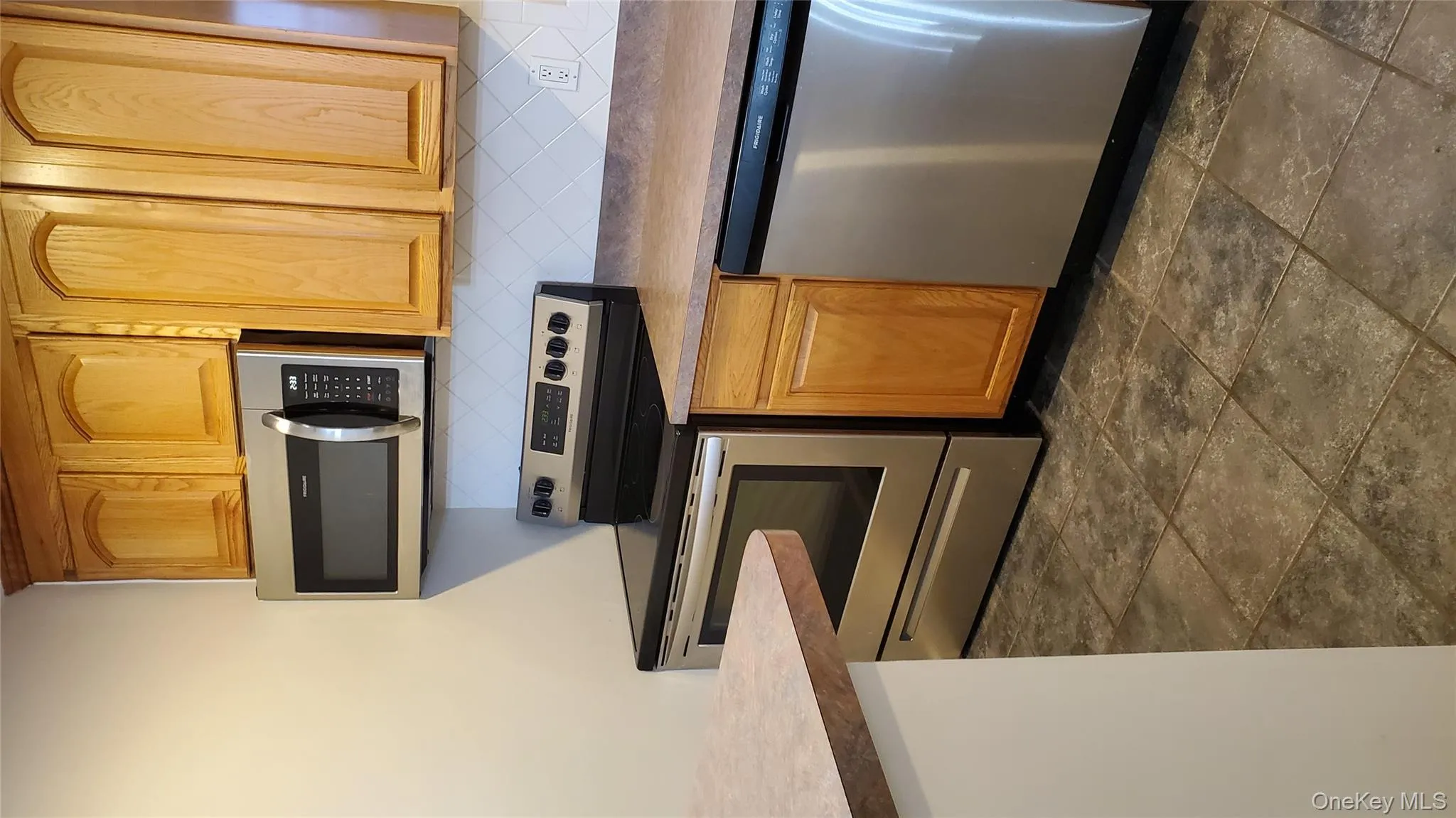 Kitchen with electric stove, dishwasher, backsplash, and light countertops Kitchen with electric stove, dishwasher, backsplash, and light countertops