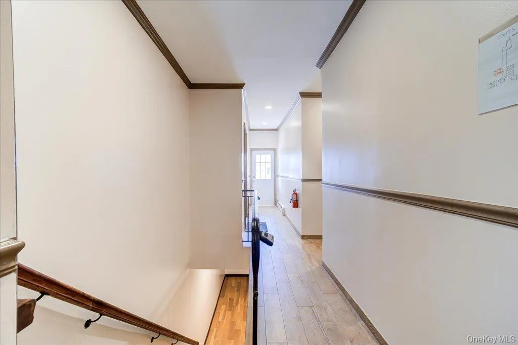 Corridor featuring crown molding, light wood-style floors, an upstairs landing, and recessed lighting Corridor featuring crown molding, light wood-style floors, an upstairs landing, and recessed lighting