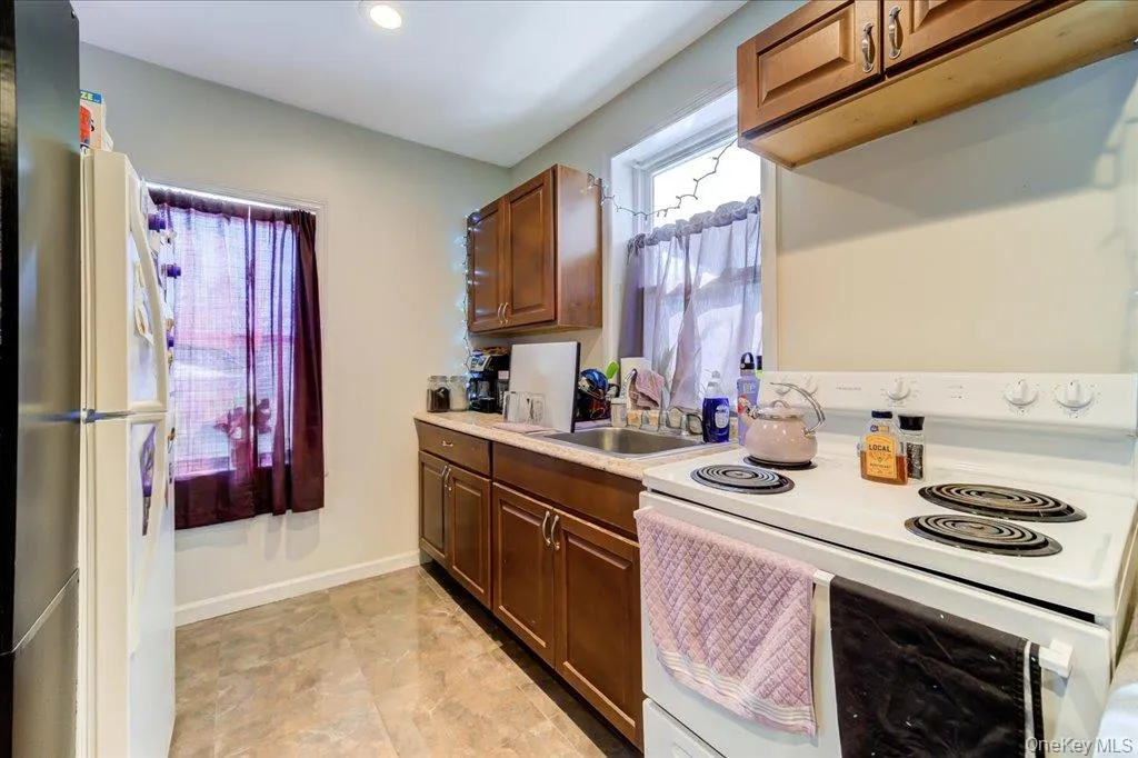 Kitchen with white appliances, light countertops, brown cabinetry, and recessed lighting Kitchen with white appliances, light countertops, brown cabinetry, and recessed lighting