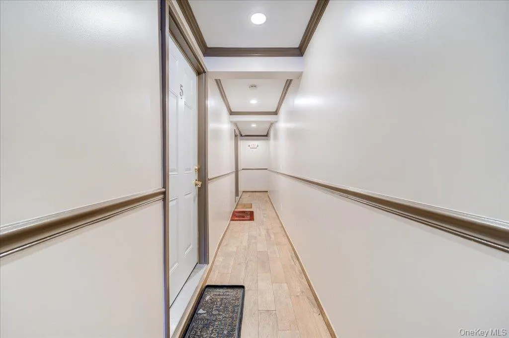 Hall with ornamental molding, light wood-style flooring, and recessed lighting Hall with ornamental molding, light wood-style flooring, and recessed lighting