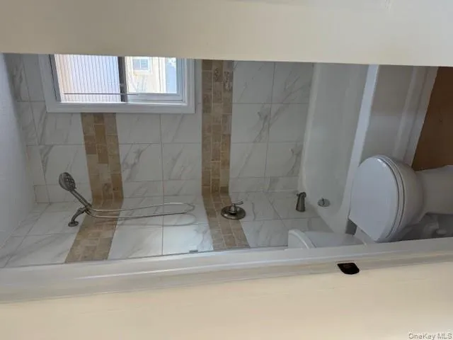 Bathroom featuring shower / washtub combination and toilet Bathroom featuring shower / washtub combination and toilet