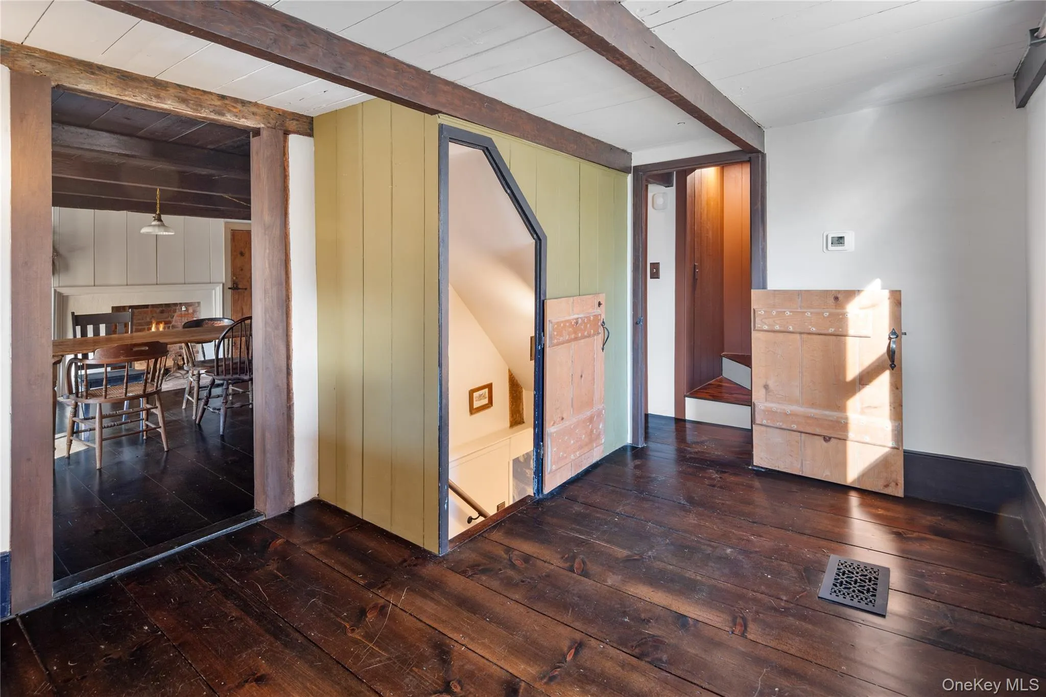 Spacious entryway showcasing the gleaming newly finished original dark wood wide plank hardwood flooring that is throughout home and exposed beams Spacious entryway showcasing the gleaming newly finished original dark wood wide plank hardwood flooring that is throughout home and exposed beams