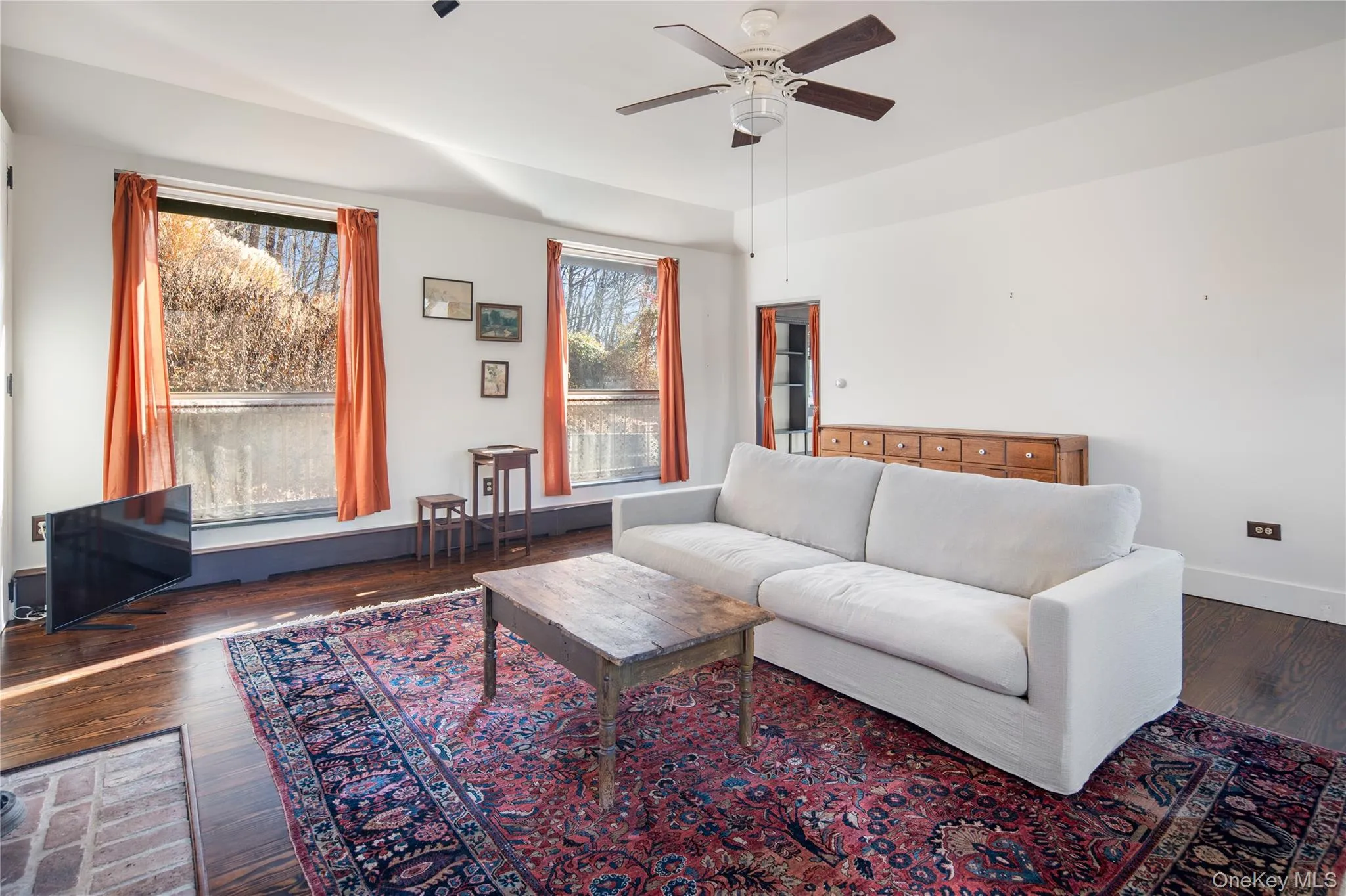 additional living area in back of home, or possible primary bedroom, featuring massive floor to ceiling windows that flood the space with natural light, track lighting, a ceiling fan, hardwood flooring and cast iron Jotul wood-burning stove insert in fireplace additional living area in back of home, or possible primary bedroom, featuring massive floor to ceiling windows that flood the space with natural light, track lighting, a ceiling fan, hardwood flooring and cast iron Jotul wood-burning stove insert in fireplace