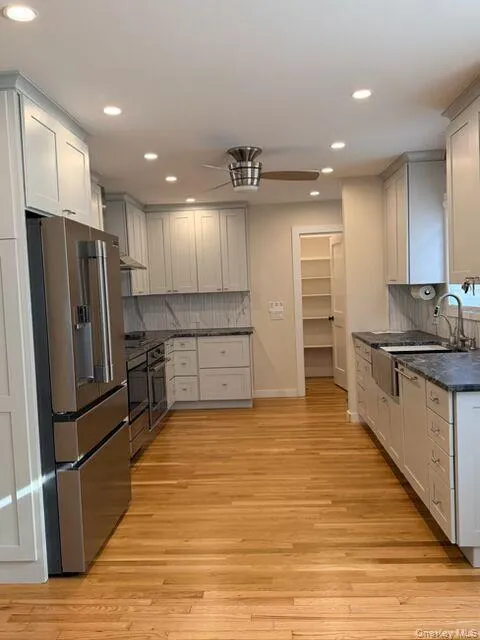 Kitchen featuring appliances with stainless steel finishes, recessed lighting, light wood-type flooring, decorative backsplash, and gray cabinets Kitchen featuring appliances with stainless steel finishes, recessed lighting, light wood-type flooring, decorative backsplash, and gray cabinets