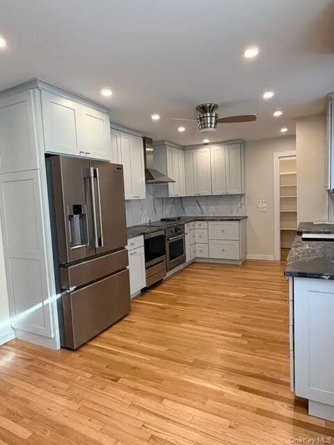 Kitchen featuring high quality fridge, light wood finished floors, decorative backsplash, dark stone counters, and recessed lighting Kitchen featuring high quality fridge, light wood finished floors, decorative backsplash, dark stone counters, and recessed lighting
