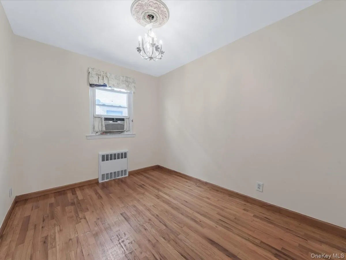 3rd Bedroom with light wood finished floors, radiator, a chandelier, and cooling unit 3rd Bedroom with light wood finished floors, radiator, a chandelier, and cooling unit