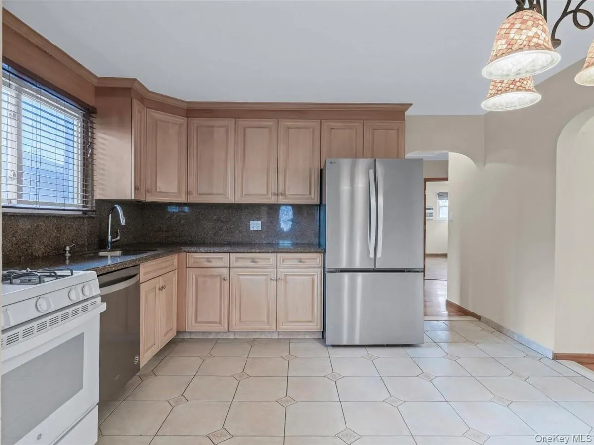 Kitchen with appliances with stainless steel finishes, dark stone counters, tasteful backsplash, arched walkways, and decorative light fixtures Kitchen with appliances with stainless steel finishes, dark stone counters, tasteful backsplash, arched walkways, and decorative light fixtures