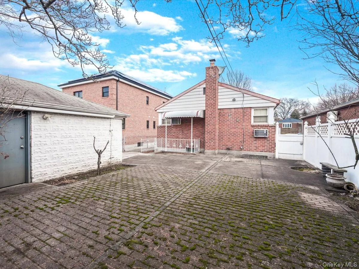 Back of house featuring a chimney, brick siding, and a patio area Back of house featuring a chimney, brick siding, and a patio area