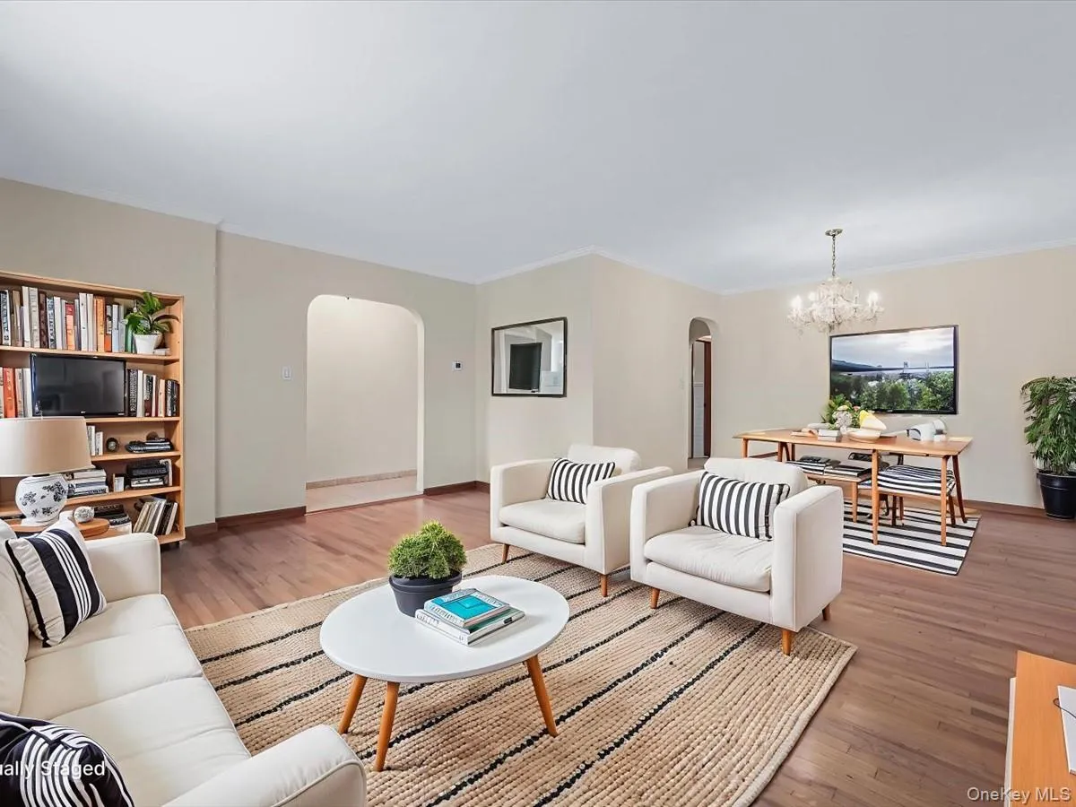 Living room featuring arched walkways, wood finished floors, a chandelier, and crown molding Living room featuring arched walkways, wood finished floors, a chandelier, and crown molding