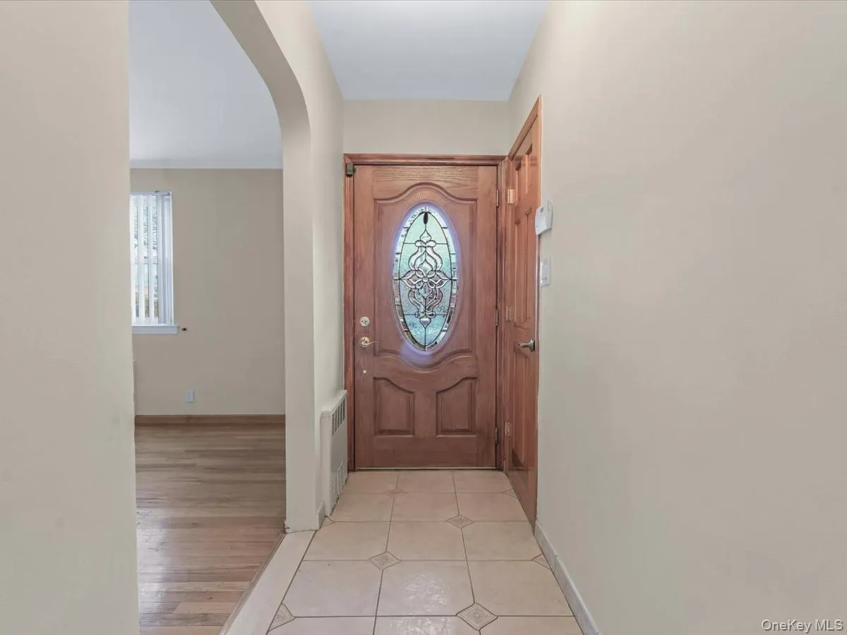 Doorway to outside featuring arched walkways, tile patterned flooring, and radiator heating unit Doorway to outside featuring arched walkways, tile patterned flooring, and radiator heating unit