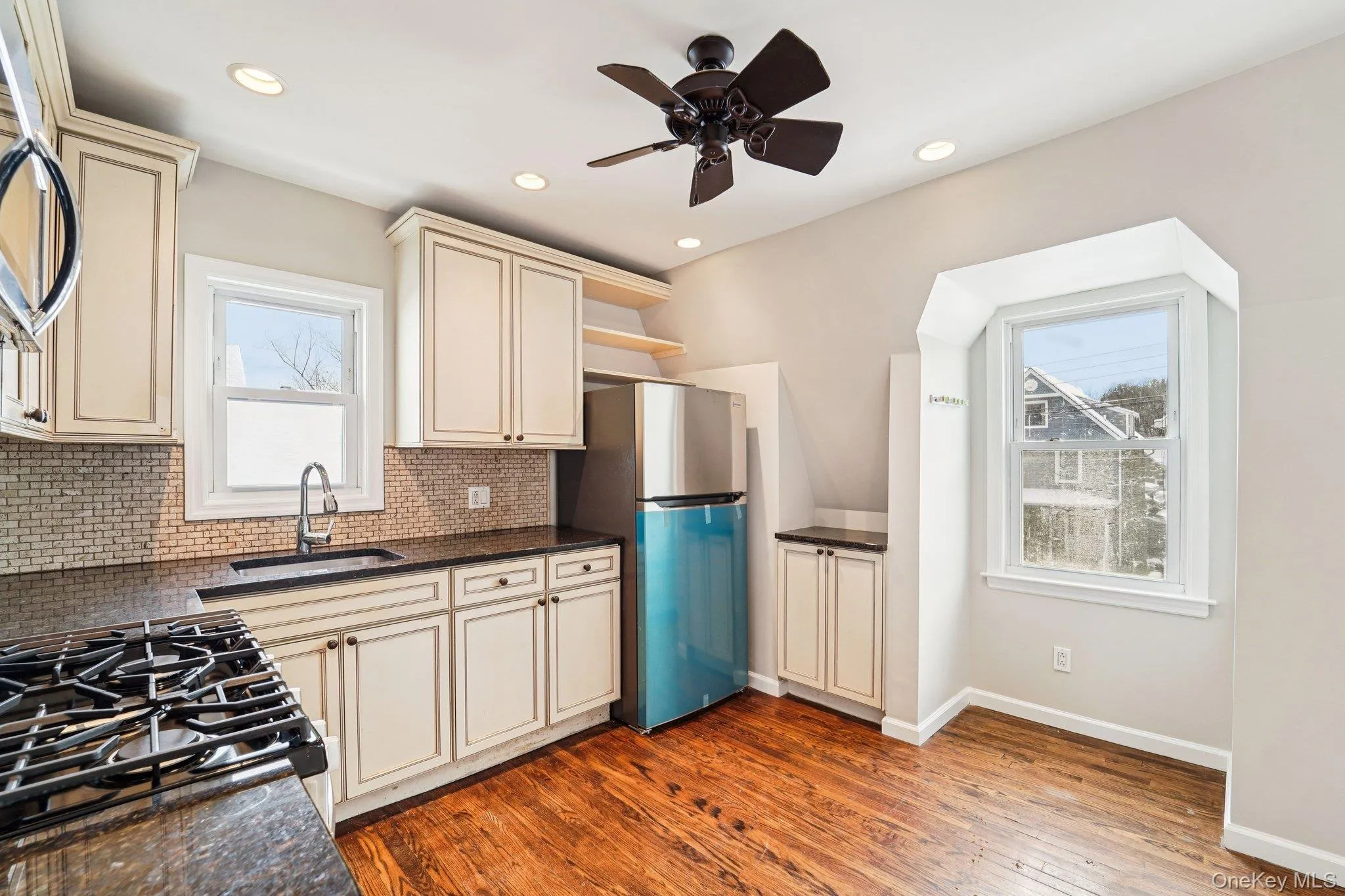 Kitchen featuring cream cabinets, open shelves, backsplash, healthy amount of natural light, and recessed lighting Kitchen featuring cream cabinets, open shelves, backsplash, healthy amount of natural light, and recessed lighting
