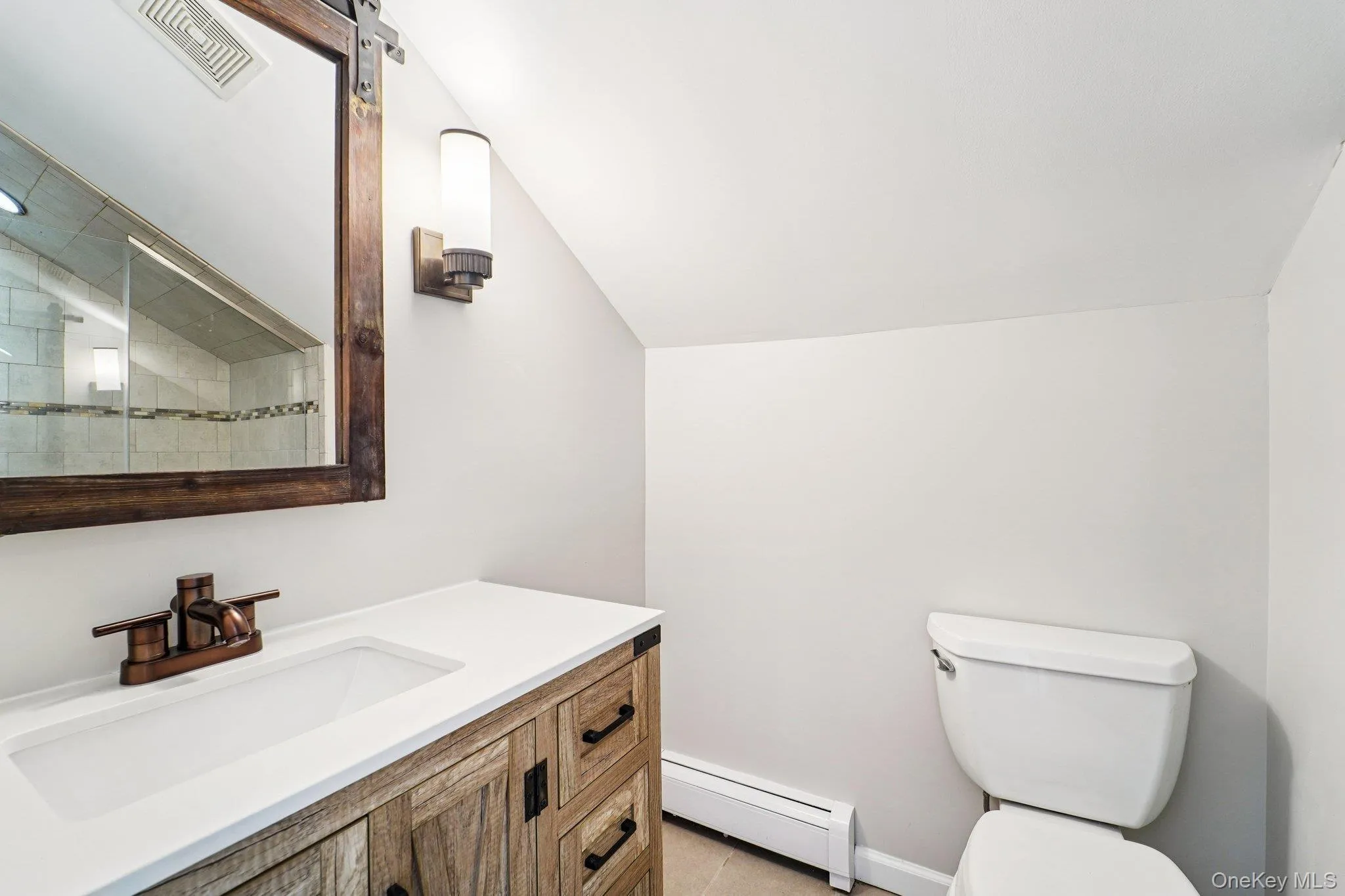 Full bath featuring a baseboard heating unit, vanity, vaulted ceiling, and a shower Full bath featuring a baseboard heating unit, vanity, vaulted ceiling, and a shower