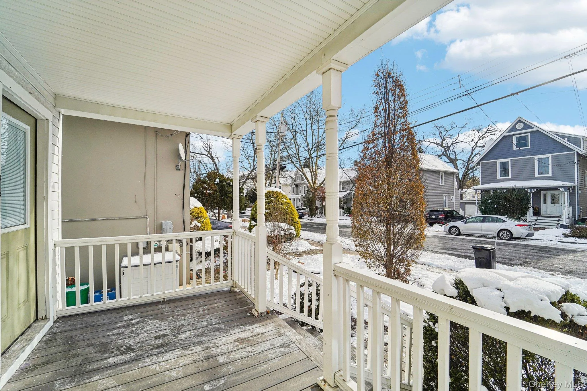 Snow covered deck with a porch and a residential view Snow covered deck with a porch and a residential view