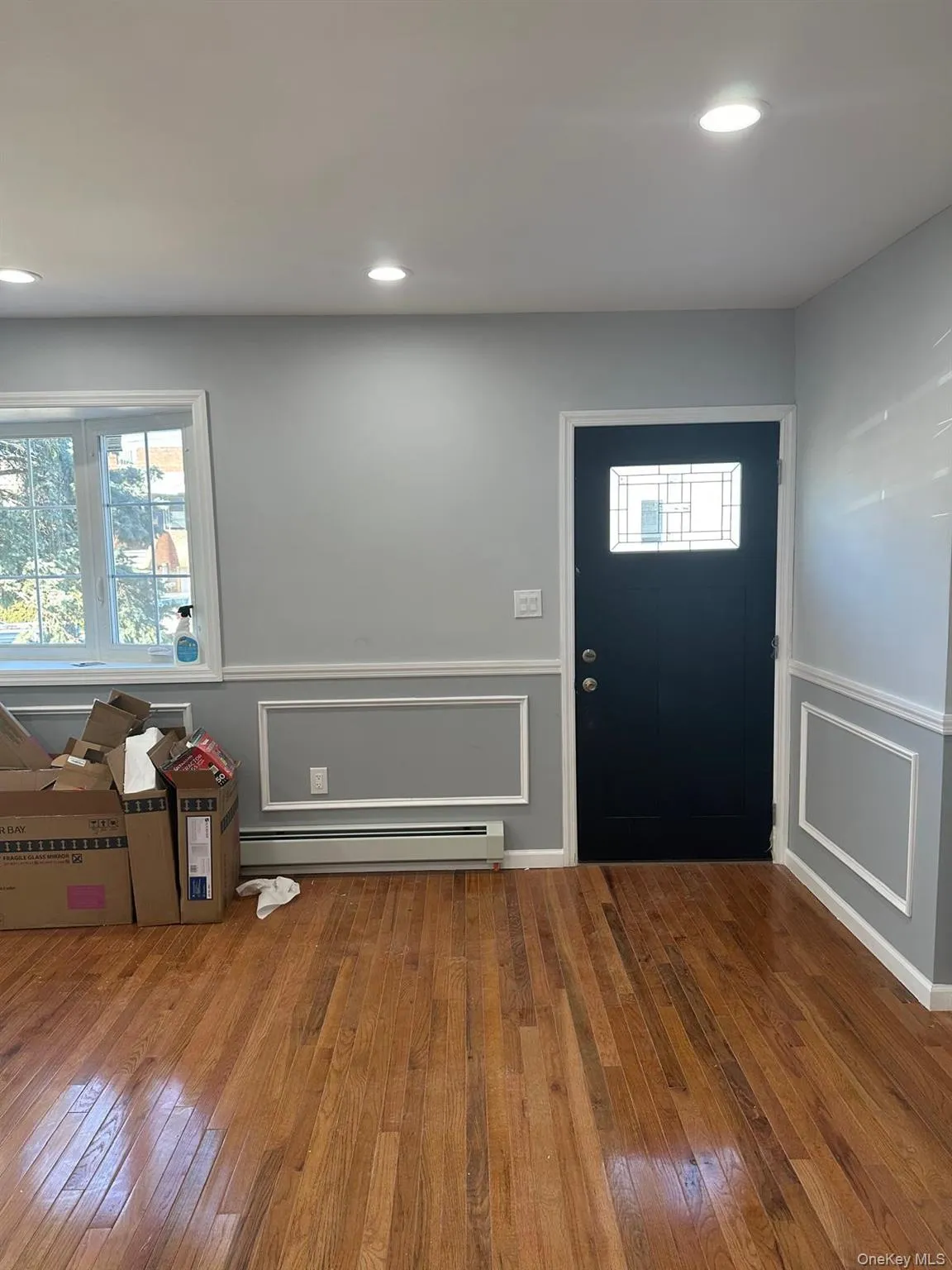 Entryway featuring a decorative wall, a wainscoted wall, hardwood / wood-style flooring, baseboard heating, and plenty of natural light Entryway featuring a decorative wall, a wainscoted wall, hardwood / wood-style flooring, baseboard heating, and plenty of natural light