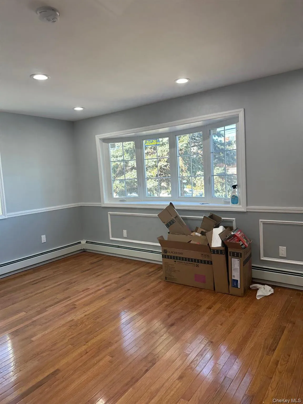 Unfurnished room with light wood finished floors, a baseboard heating unit, a smoke detector, and recessed lighting Unfurnished room with light wood finished floors, a baseboard heating unit, a smoke detector, and recessed lighting