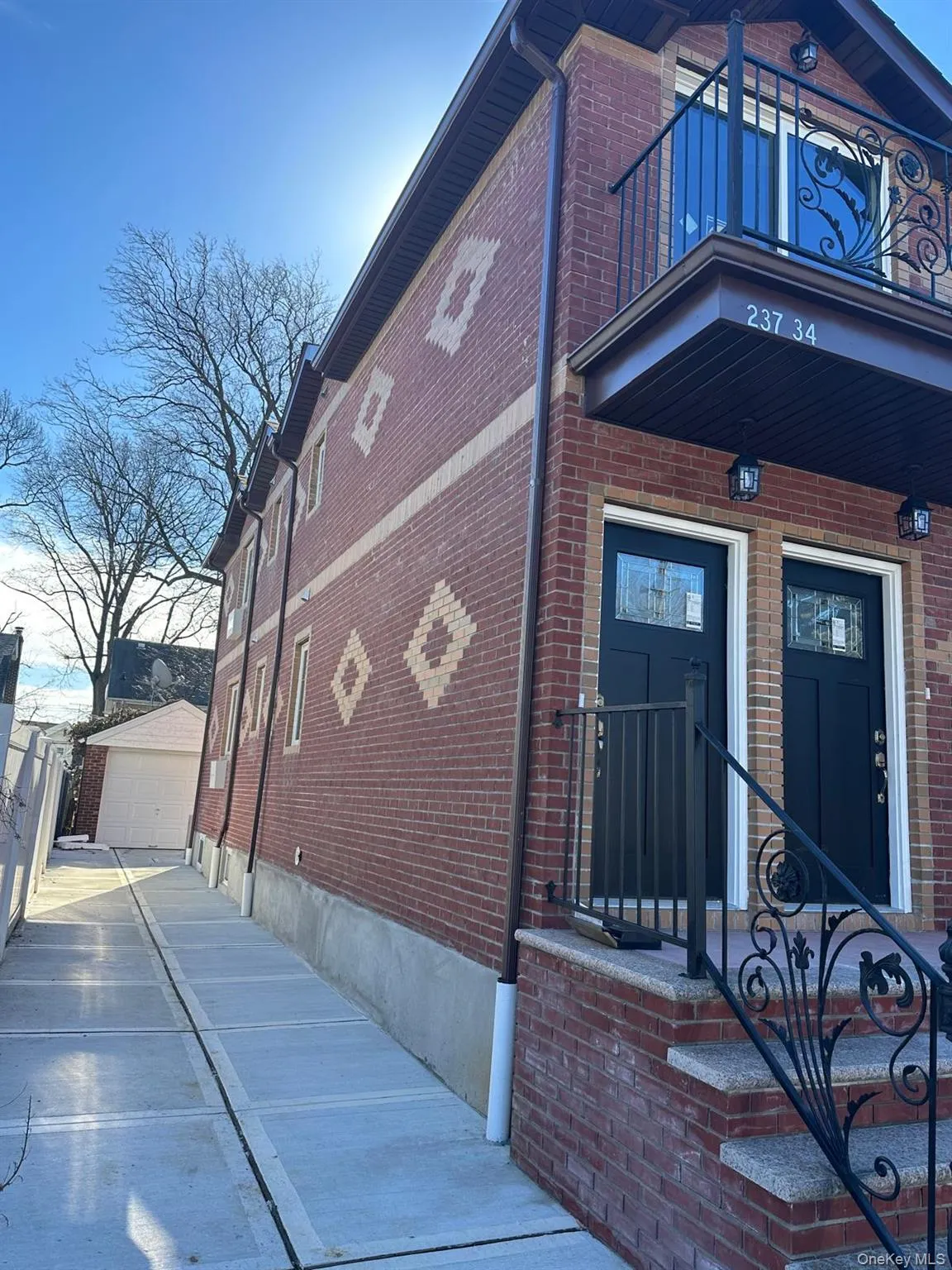 View of home's exterior featuring brick siding, a garage, an outdoor structure, and a balcony View of home's exterior featuring brick siding, a garage, an outdoor structure, and a balcony