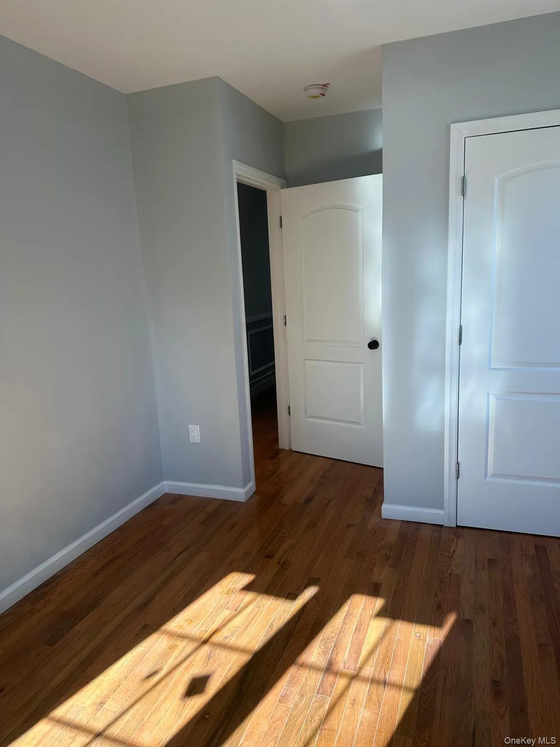 Unfurnished bedroom with dark wood-style floors and baseboards Unfurnished bedroom with dark wood-style floors and baseboards