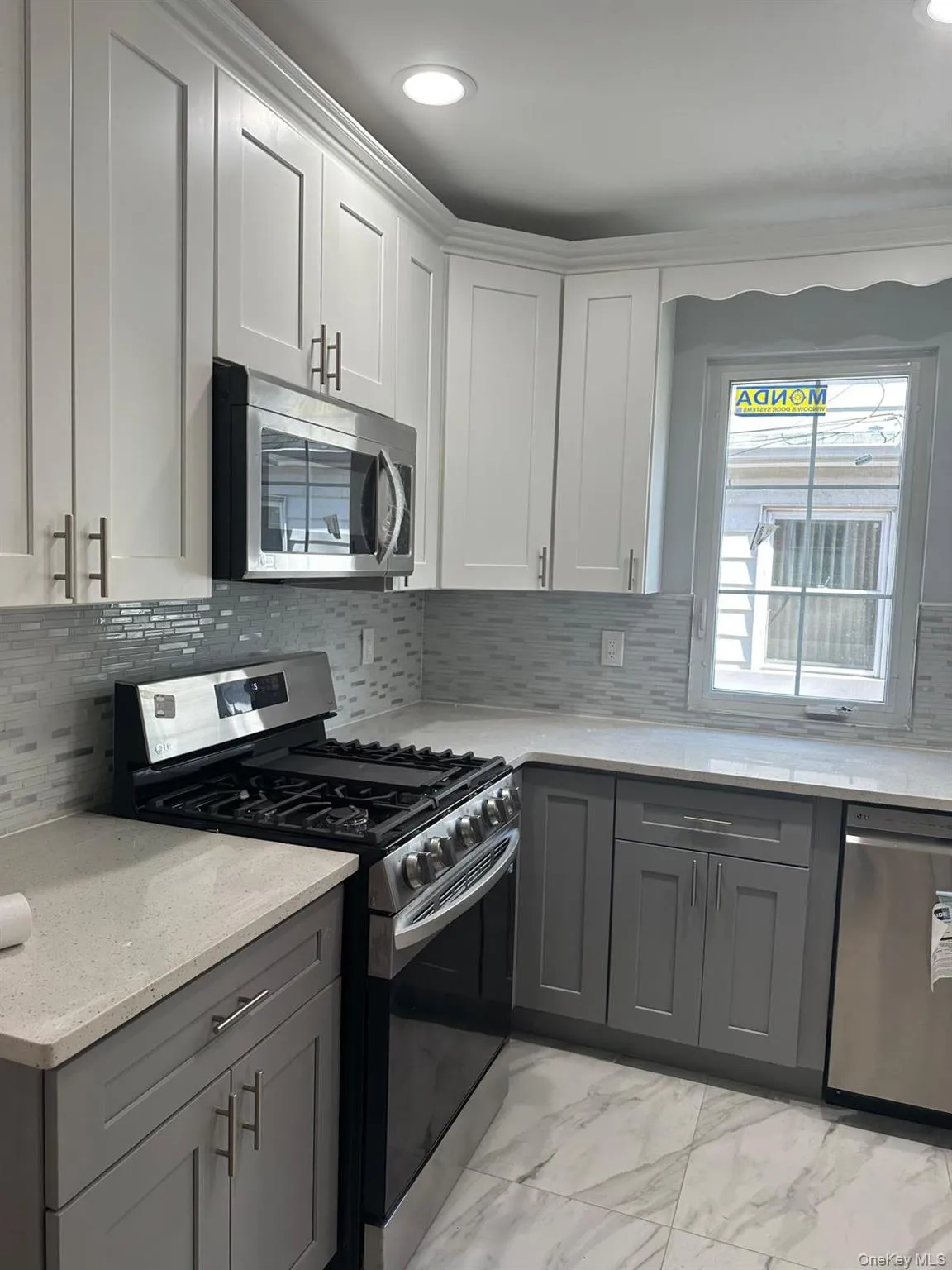 Kitchen with appliances with stainless steel finishes, gray cabinets, light marble finish flooring, light stone counters, and recessed lighting Kitchen with appliances with stainless steel finishes, gray cabinets, light marble finish flooring, light stone counters, and recessed lighting