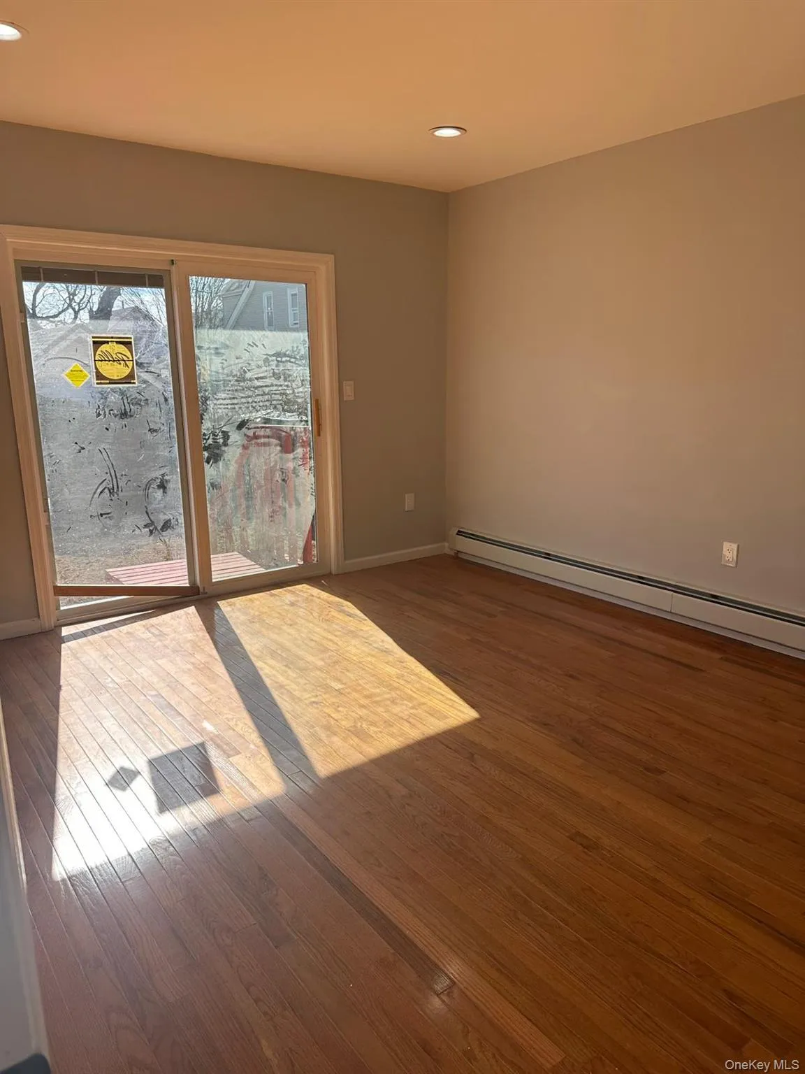 Spare room featuring a baseboard heating unit, recessed lighting, and dark wood-style flooring Spare room featuring a baseboard heating unit, recessed lighting, and dark wood-style flooring