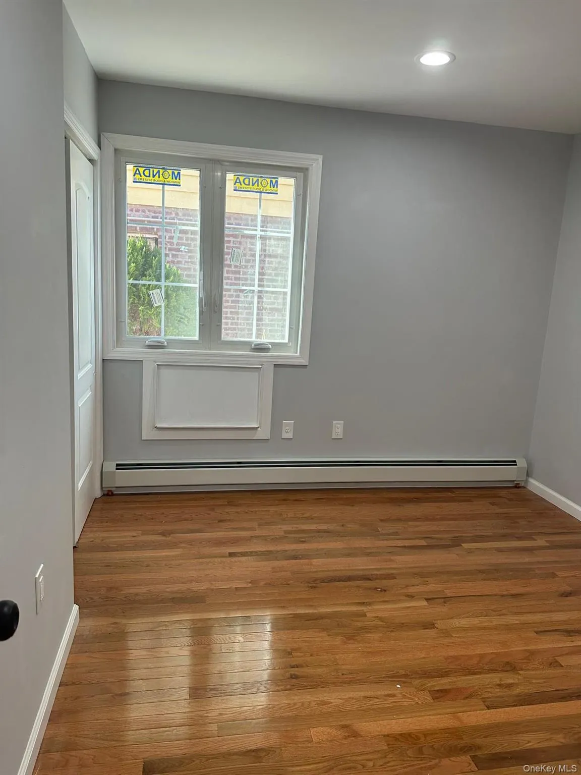 Empty room featuring wood-type flooring, a baseboard radiator, and recessed lighting Empty room featuring wood-type flooring, a baseboard radiator, and recessed lighting