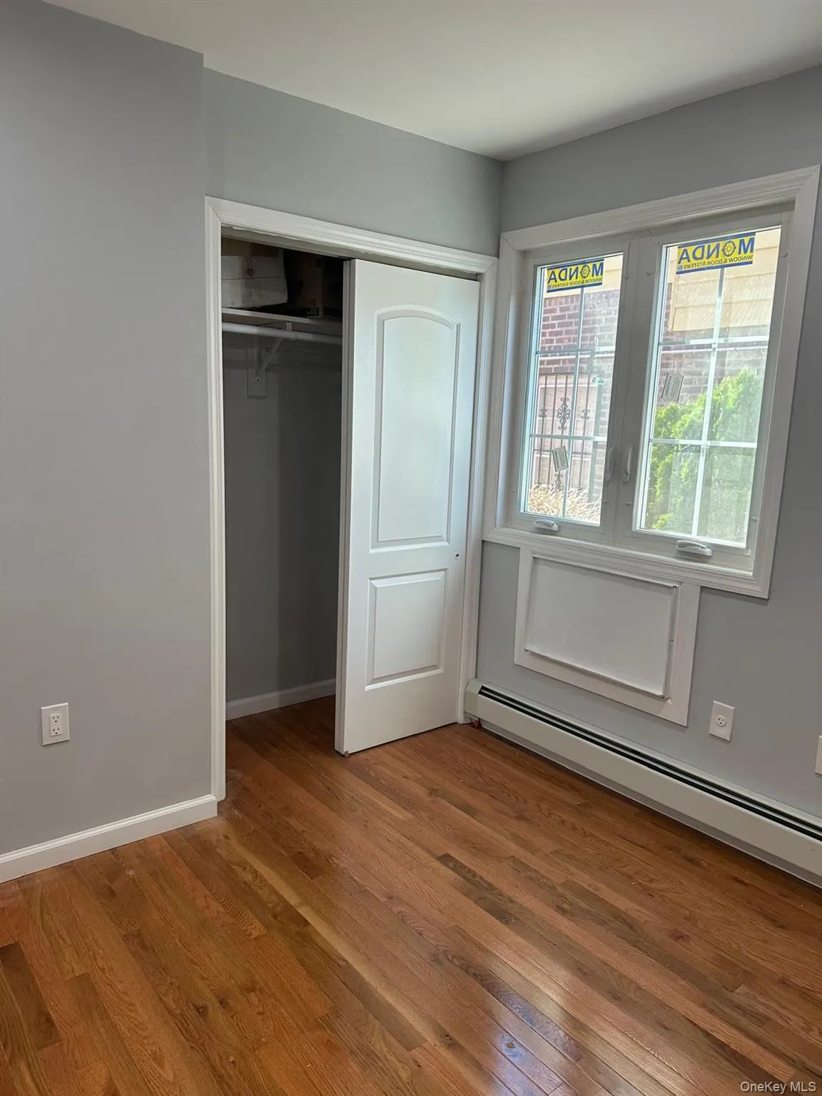 Unfurnished bedroom featuring a baseboard heating unit, hardwood / wood-style flooring, and a closet Unfurnished bedroom featuring a baseboard heating unit, hardwood / wood-style flooring, and a closet