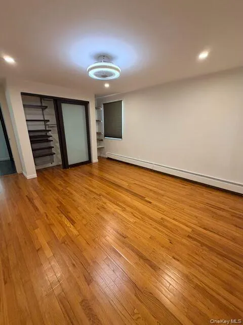 Unfurnished bedroom with light wood-style floors, a baseboard heating unit, recessed lighting, and a closet Unfurnished bedroom with light wood-style floors, a baseboard heating unit, recessed lighting, and a closet