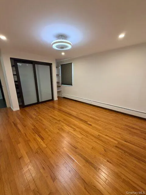 Unfurnished bedroom with baseboard heating, light wood-type flooring, recessed lighting, and a closet Unfurnished bedroom with baseboard heating, light wood-type flooring, recessed lighting, and a closet