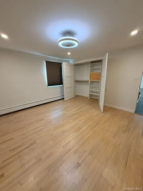 Unfurnished bedroom featuring recessed lighting, a baseboard radiator, light wood finished floors, and a closet Unfurnished bedroom featuring recessed lighting, a baseboard radiator, light wood finished floors, and a closet