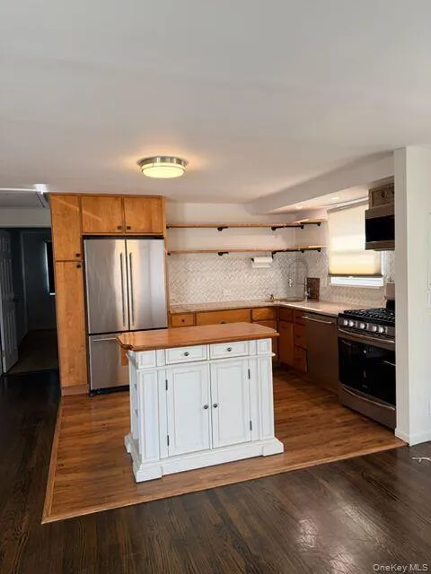 Kitchen with stainless steel appliances, open shelves, dark wood-type flooring, a kitchen island, and white cabinets Kitchen with stainless steel appliances, open shelves, dark wood-type flooring, a kitchen island, and white cabinets