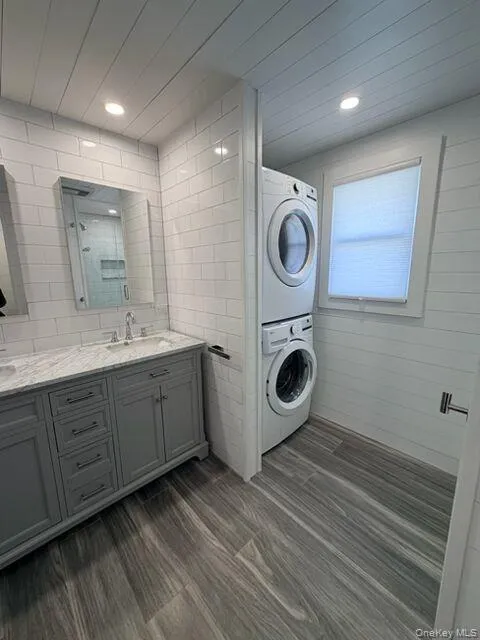 Washroom featuring stacked washer / dryer and dark wood-type flooring Washroom featuring stacked washer / dryer and dark wood-type flooring