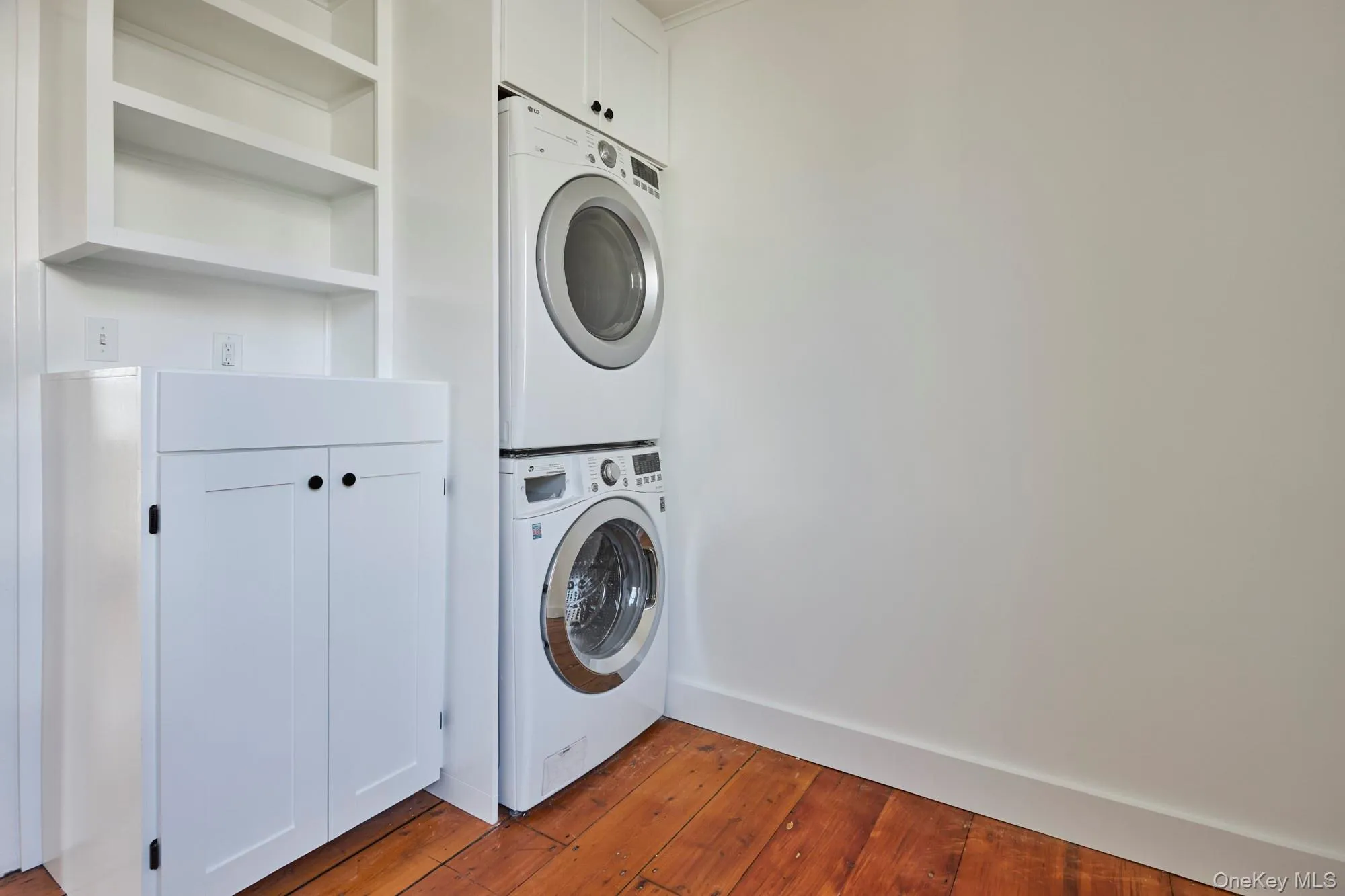 Laundry area with estacked washer and dryer and dark wood-type flooring Laundry area with estacked washer and dryer and dark wood-type flooring
