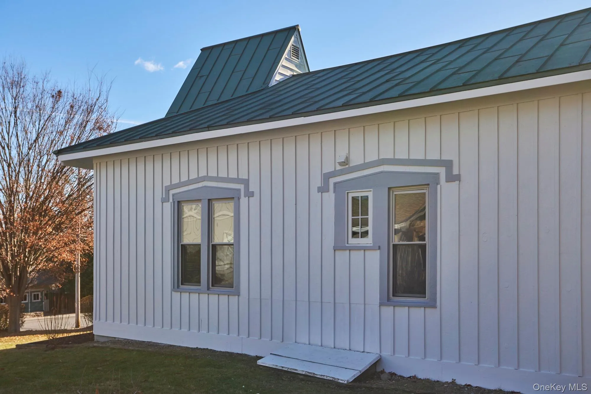 View of side of home with a standing seam roof, board and batten siding, a metal roof, and a lawn View of side of home with a standing seam roof, board and batten siding, a metal roof, and a lawn
