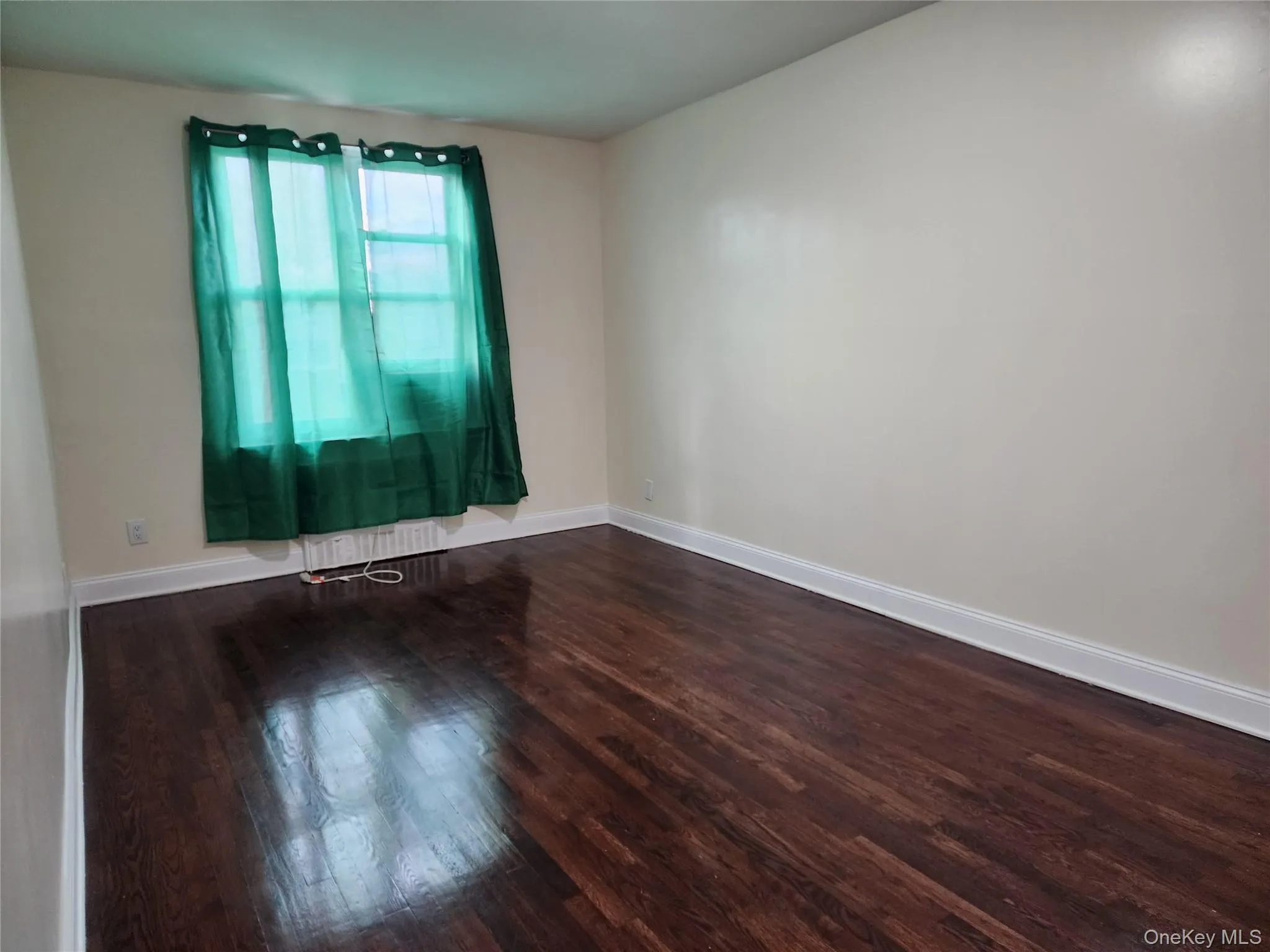 Spare room with baseboards and dark wood-type flooring Spare room with baseboards and dark wood-type flooring