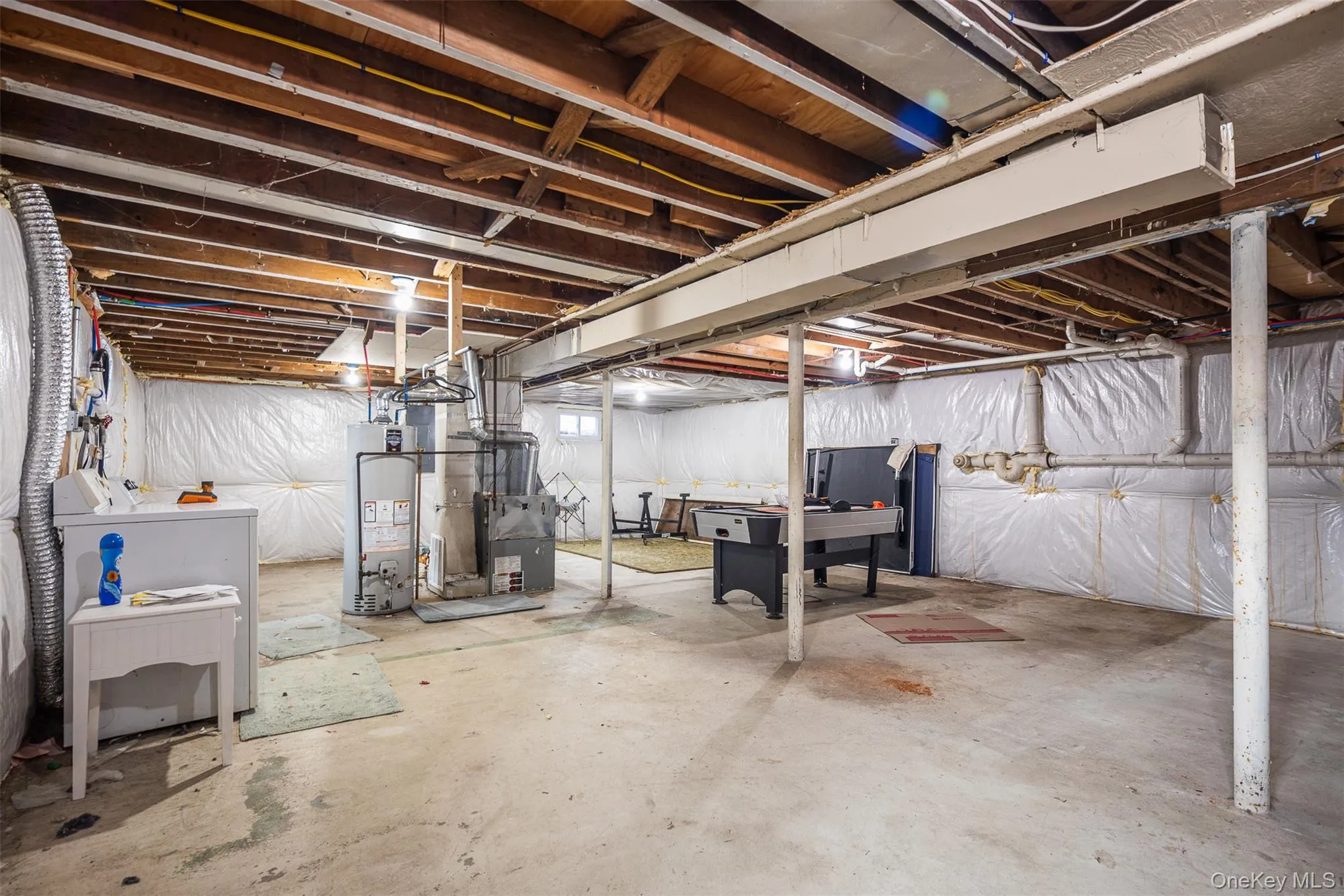 Unfinished below grade area with washer / clothes dryer and water heater Unfinished below grade area with washer / clothes dryer and water heater