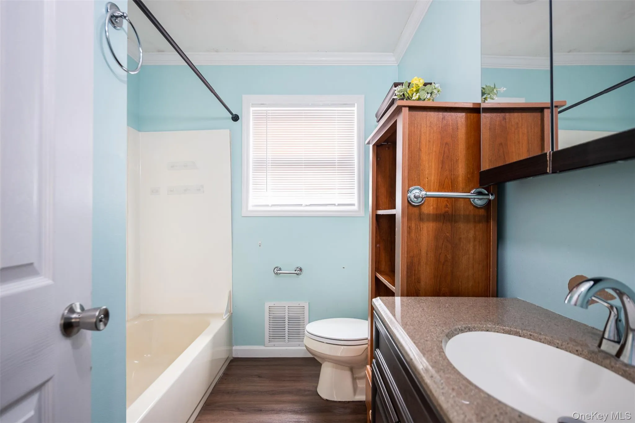 Bathroom with vanity, bathtub / shower combination, dark wood-style flooring, and ornamental molding Bathroom with vanity, bathtub / shower combination, dark wood-style flooring, and ornamental molding