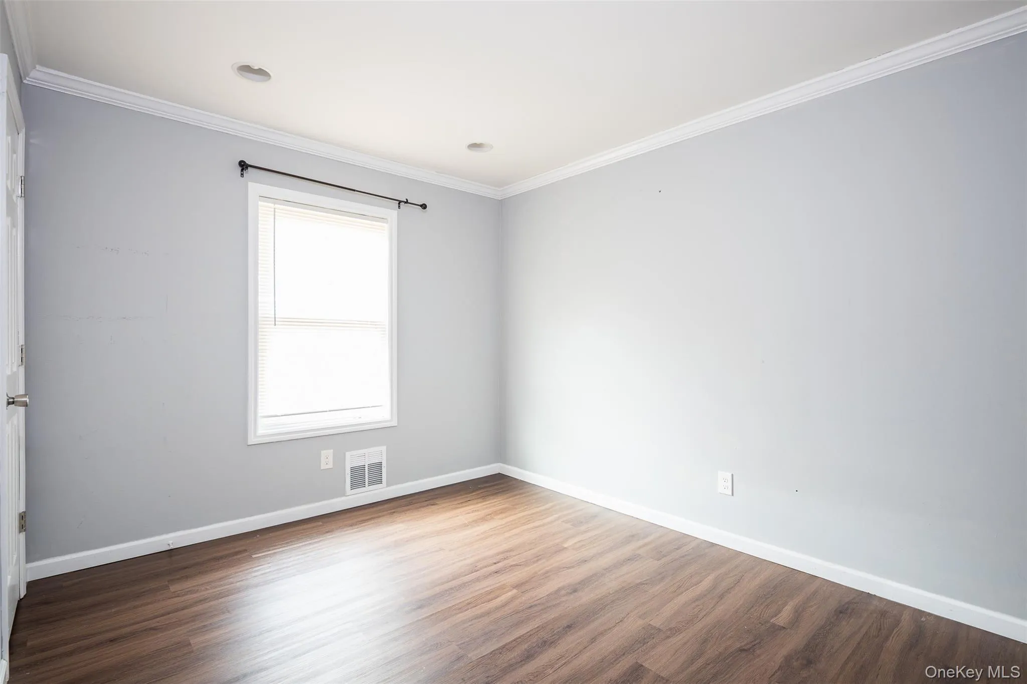 Empty room with ornamental molding and dark wood-style flooring Empty room with ornamental molding and dark wood-style flooring